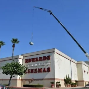 A crane lifts an HVAC unit onto the roof of an Edwards Stadium Cinemas building.